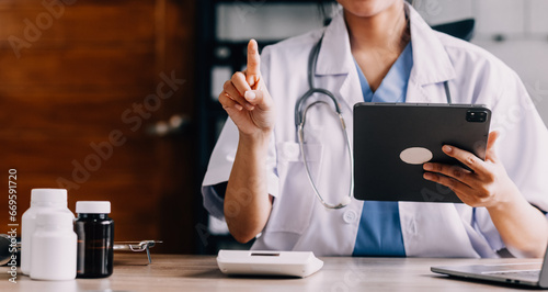 Concerned young female Caucasian doctor in white medical uniform sit at desk in hospital work on laptop, focused woman nurse or GP busy fill anamnesis on computer gadget, medicine, technology concept
