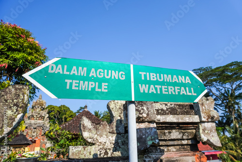 Green signposts with directions to the hindus temple or to the Tibumana Waterfall in Bali, Indonesia. Signboard instruction for tourist at travel destination. photo