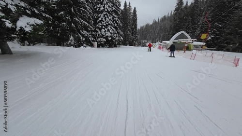 Skiing. Action camera low angle view of skis of skier going downhill on alpine ski on snow slopes in the mountains. Man going downhill on ski having fun on slopes. Winter sport outdoor activity video