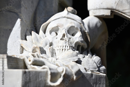 Partial view to a weathered, white sandstone sculpture of a male skull on a cemetery in Weimar-Germany.  photo