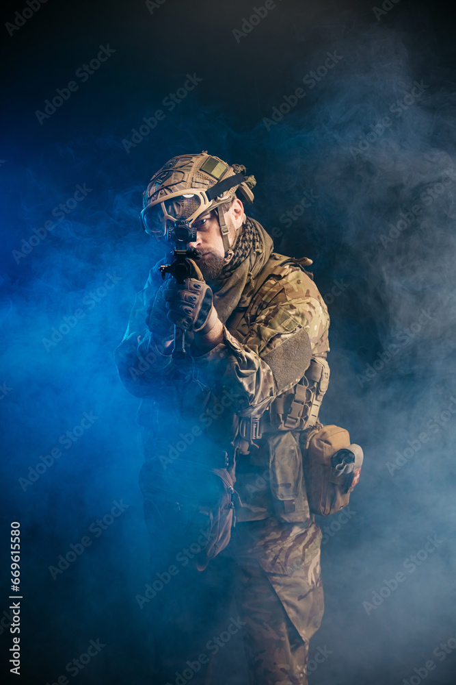 A courageous soldier in a protective combat uniform with a machine gun, standing on a dark background, shrouded in smoke. War and military concept.Computer games.