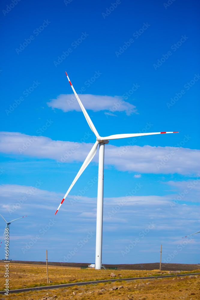 Fleet of power generators in motion. The blades of the wind farm rotate against the sky. The concept of extracting electricity from renewable sources. Wind turbine to generate electricity. Fleet of power generators in motion. The blades of the wind farm rotate against the sky. The concept of extracting electricity from renewable sources. Wind turbine to generate electricity.