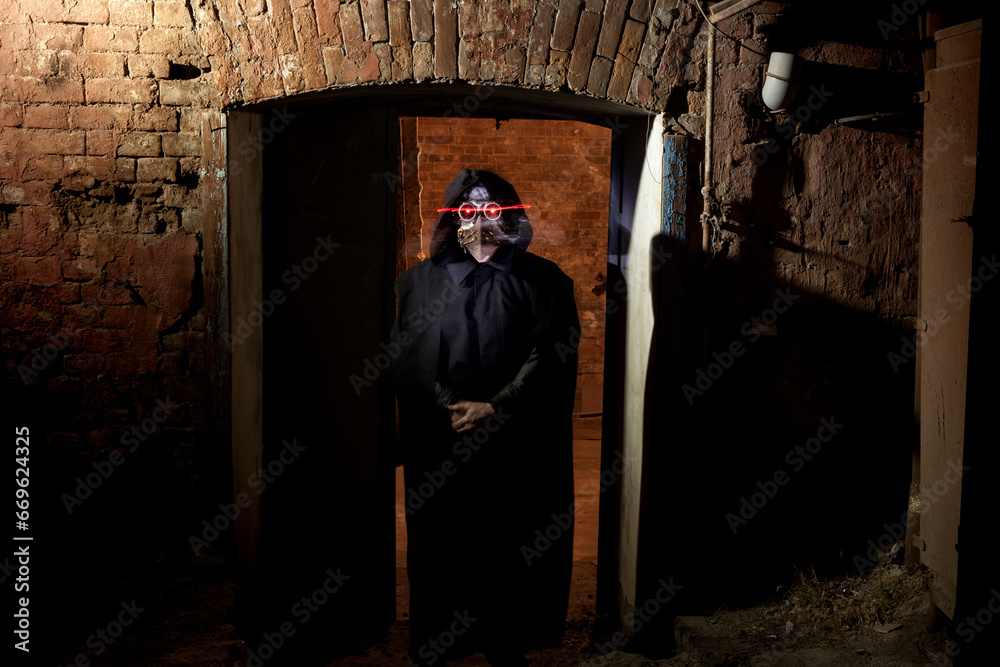 A man in a Venetian plague doctor mask with glowing red eyes against the background of an ancient house