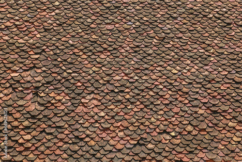 Vintage red roof terracotta tile. Old roof tiles background. Texture ancient dilapidated tiles with moss, broken, ruined tile. Red brown roof tiles in Buddhist temple near Vietnam. Top view