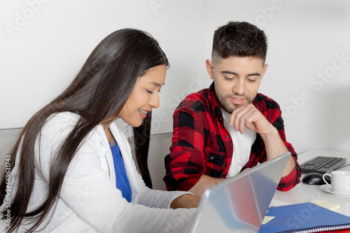Young woman with Native American features writes for her young male office colleague. Cowork concept.