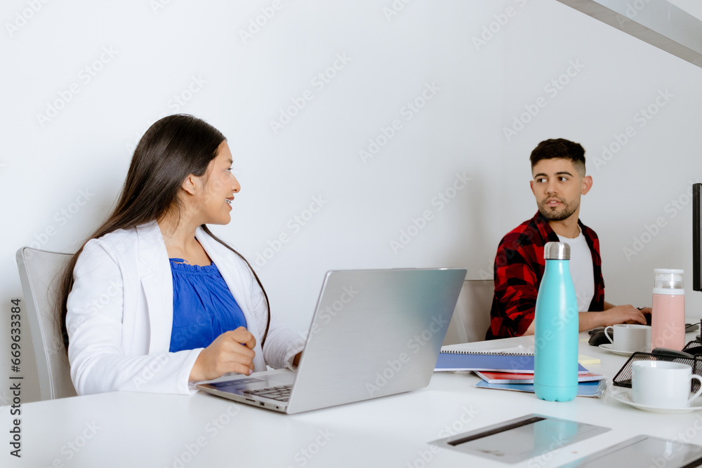 Multiethnic office colleagues chat at their desks in front of their PCs. Office concept. Multiethnic office colleagues chat at their desks in front of their PCs. Office concept.