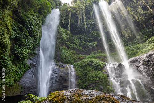 The Sekumpul Waterfall  a large waterfall in the middle of the jungle that falls into a deep green gorge. Trees and tropical plants at Bali s highest waterfall.