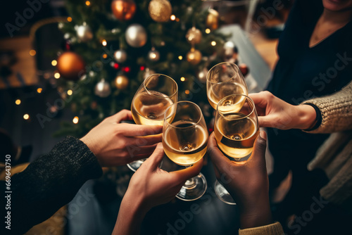 Happy multiracial friends toasting sparkling wine glasses close-up against golden bokeh lights background. Christmas celebration
