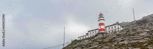 Faro de Cabo Silleiro, a lighthouse on a cape, lighthouse on the mountain, lighthouse on the hill, a lighthouse at the edge of a cliff, red and white lighthouse, lighthouse on a cloudy day photo