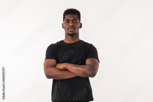 Serious african american guy portrait in a black T-shirt. Man looking aside on white studio background with copy space