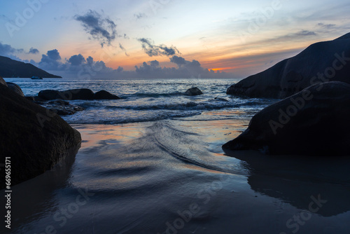 Shore water and silhouettes of coastal rocks at sunset. Mahe island, Seychelles