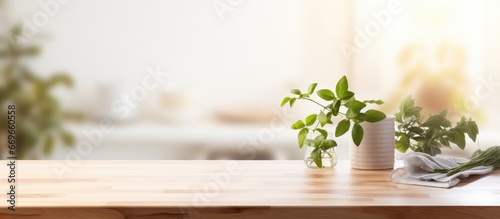 Wooden tabletop with free space for product display against blurred white kitchen with cutting board and plant in Scandinavian style lighting