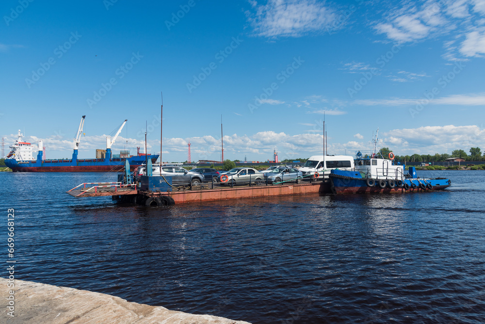 ferry crossing consisting of a barge and tug that manages a barge that transports vehicles from one shore to another. in the north of Russia, in the Arkhangelsk region.