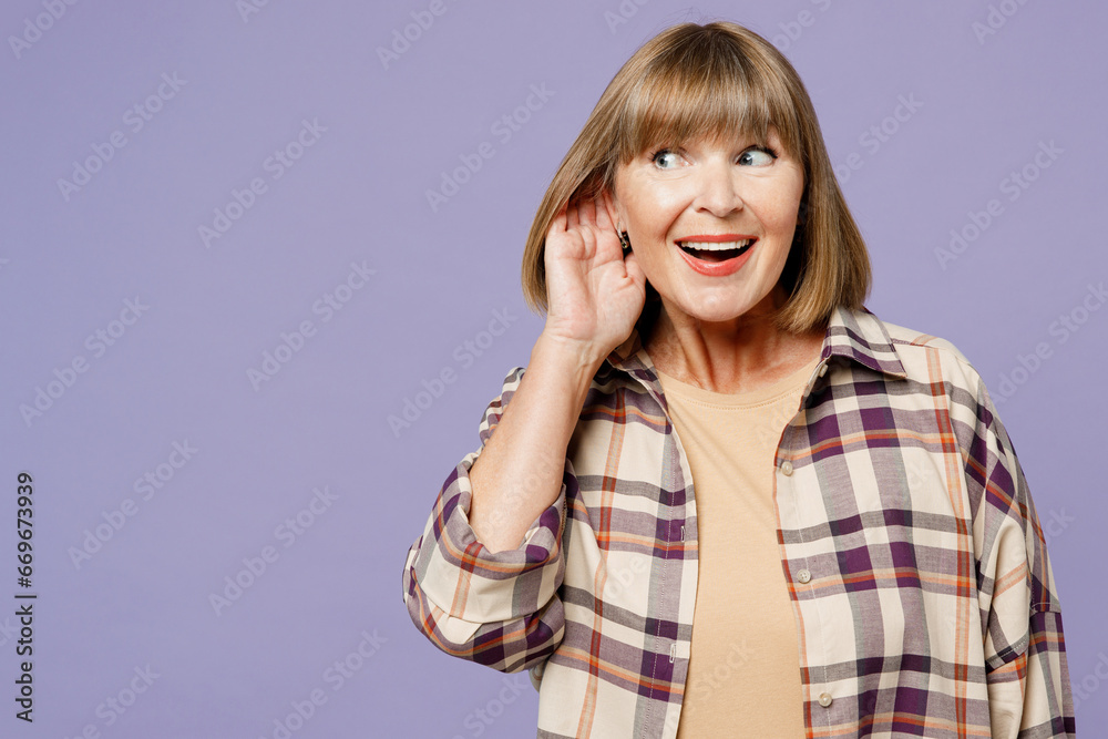 Elderly curious nosy gray-haired woman 50s years old wear beige t-shirt shirt casual clothes try to hear you overhear listening intently isolated on plain pastel purple background. Lifestyle concept. Elderly curious nosy gray-haired woman 50s years old wear beige t-shirt shirt casual clothes try to hear you overhear listening intently isolated on plain pastel purple background. Lifestyle concept.