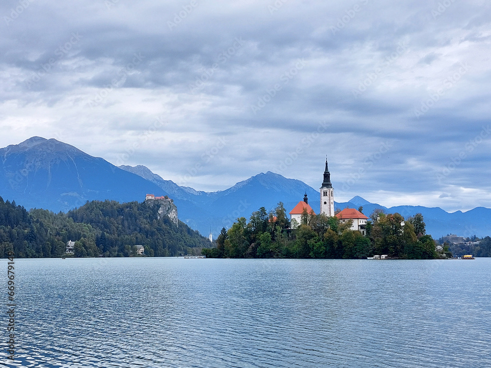 white church on island on lake Bled. Dark blue mountains. Slovenia.