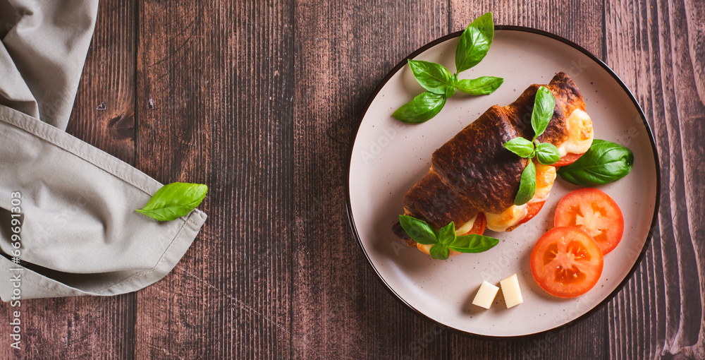 Baked caprese croissant with tomatoes, cheese and basil on a plate top view web banner Baked caprese croissant with tomatoes, cheese and basil on a plate top view web banner