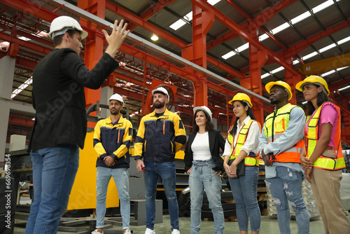 two professional engineer,worker,technician use clipboard discuss work, walk in steel metal manufacture factory plant industry. Black African American man and woman wear hard hat check quality machine