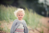 Little girl with blonde curly hair in summer on the beach 
