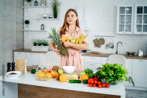 A Woman Holding a Pineapple in a Beautifully Decorated Kitchen. A woman standing in a kitchen holding a pineapple