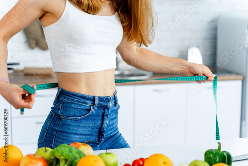 A Woman Measuring Her Waist with a Tape photo