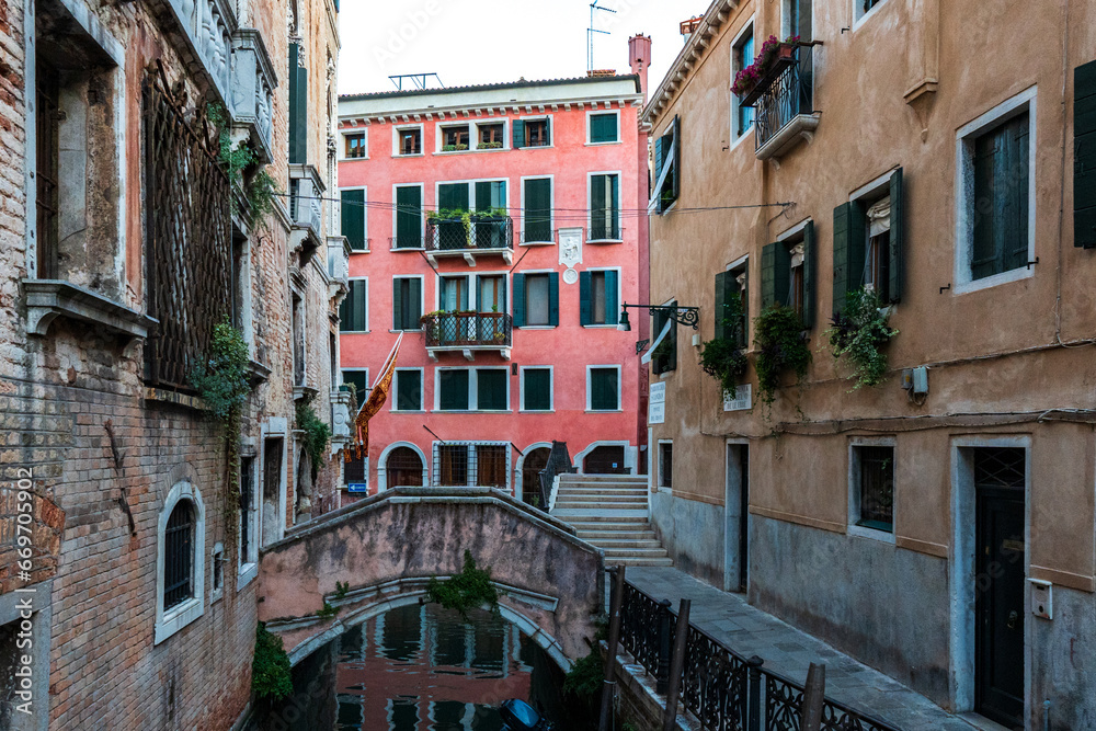 Scenic canal with bridge and ancient buildings with potted plants in Venice, Italy