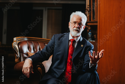 Experienced university rector confidently posing in his office. A mature and successful male professor in his 60s or 70s, embodying the essence of a respected academic leader. photo