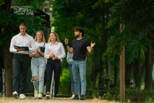 Four university students walking together with their books in their hands learning and studying outside