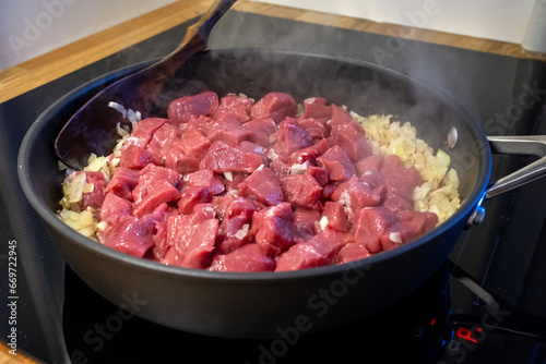 raw meat and chopped onion on cooking pan