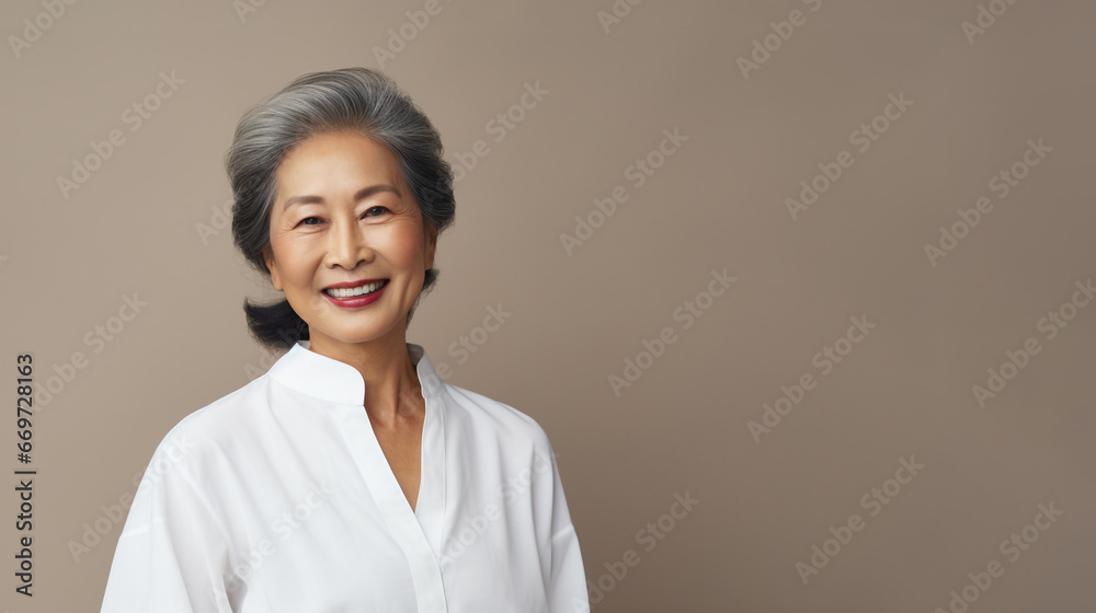 An Elderly Mature Asian Woman wearing white is isolated against a brown background with copy space, beautiful and confident An Elderly Mature Asian Woman wearing white is isolated against a brown background with copy space, beautiful and confident
