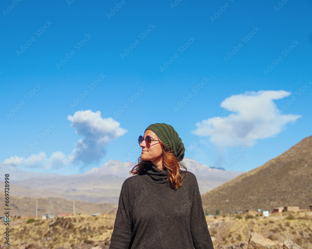 Naklejka premium mulher com fumaça de vulcões ao fundo no valle del colca, peru 