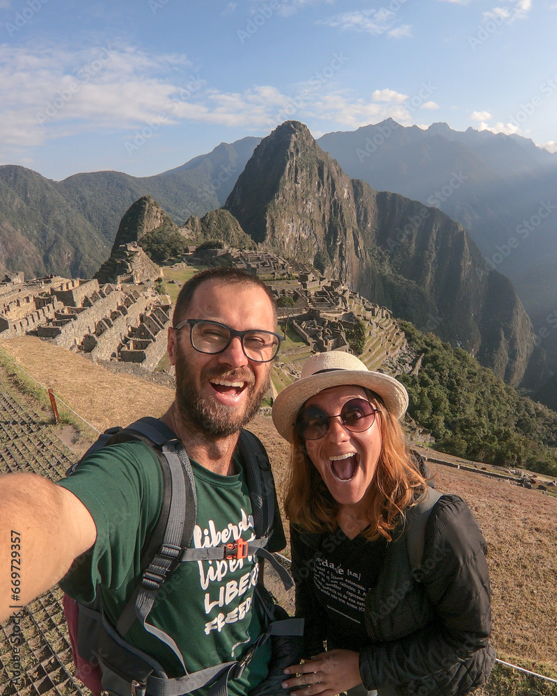 selfie de casal sorrindo em frente a montanha de machu picchu no peru 