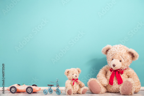 Teddy Bears, toy tricycle and old vintage plastic car front mint blue wall background. Mother or father with baby concept. Retro style filtered photo