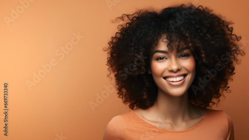 Beautiful girl smiling with curly hair and clean healthy skin on an orange background with copy space photo