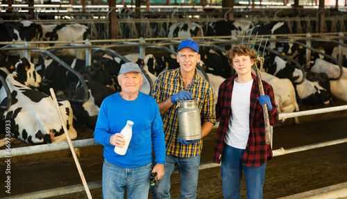 Continuity of generations - portrait of farmers of different ages against the backdrop of a cowshed