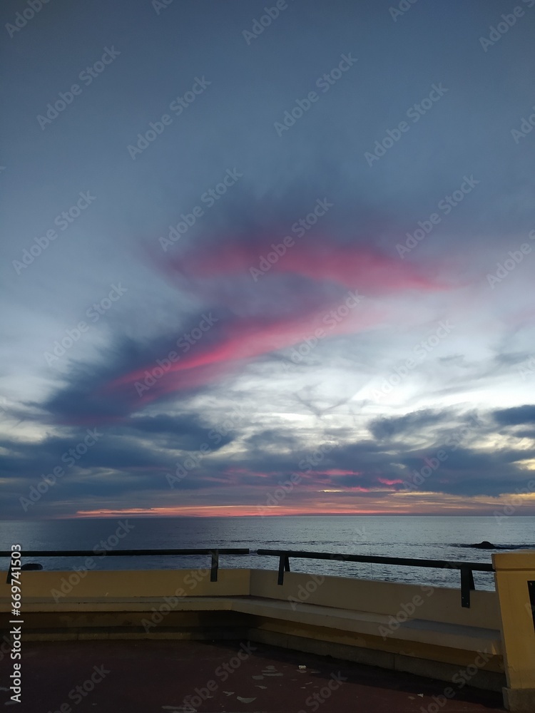 Céu pintado com as cores de um Pôr do Sol na praia.