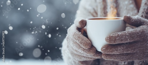 Winter concept Womens mittened hands hold a warm beverage outdoors