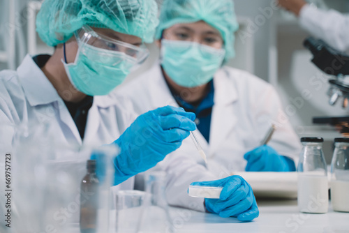 Food scientist or two researcher testing milk samples of dairy products in the laboratory. Researchers are looking and compare at the stratification of milk.