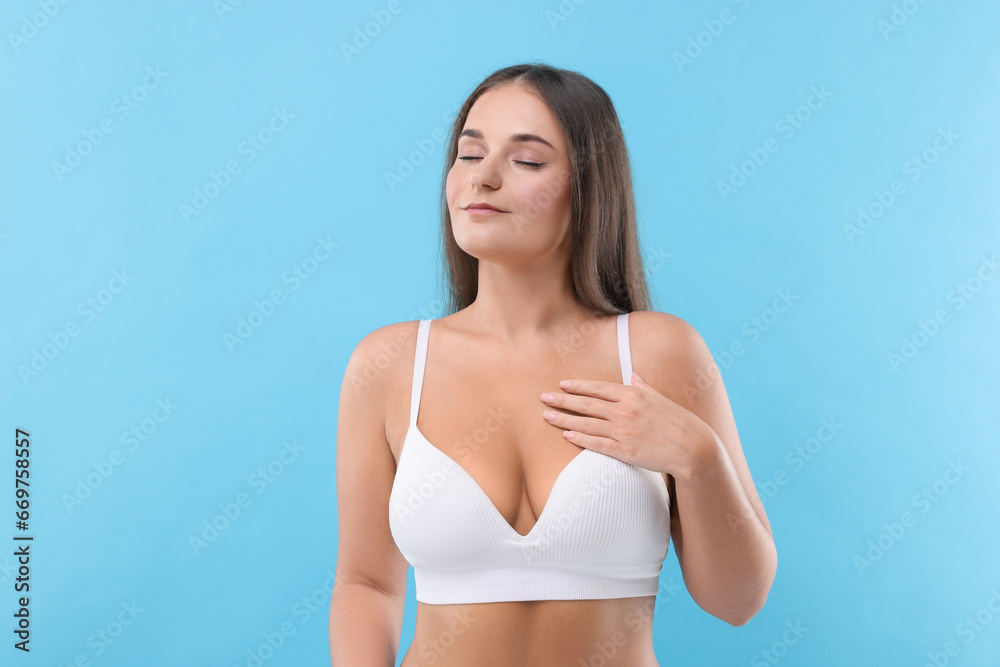 Portrait of young woman with beautiful breast on light blue background Portrait of young woman with beautiful breast on light blue background