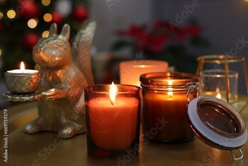 Burning candles on table in room decorated for Christmas