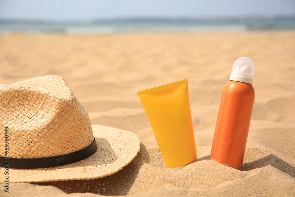 Sunscreens and straw hat on sandy beach, space for text. Sun protection Sunscreens and straw hat on sandy beach, space for text. Sun protection