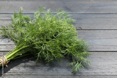 Bunch of fresh green dill on grey wooden table, closeup. Space for text