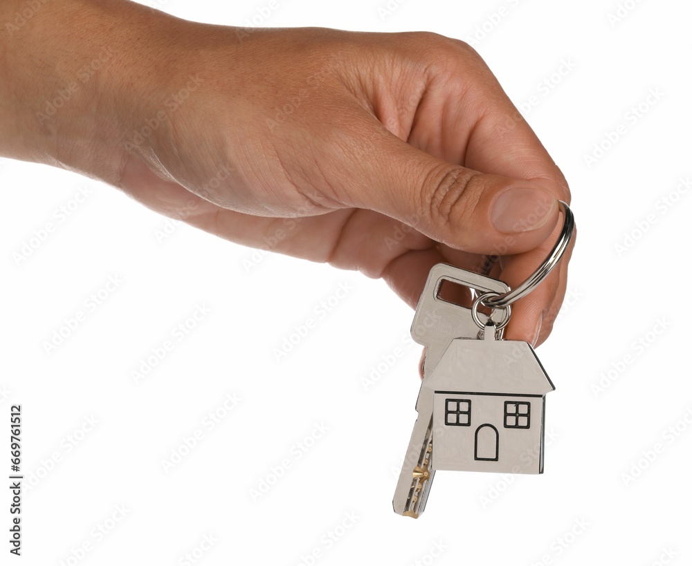 Woman holding key with metallic keychain in shape of house on white background, closeup Woman holding key with metallic keychain in shape of house on white background, closeup