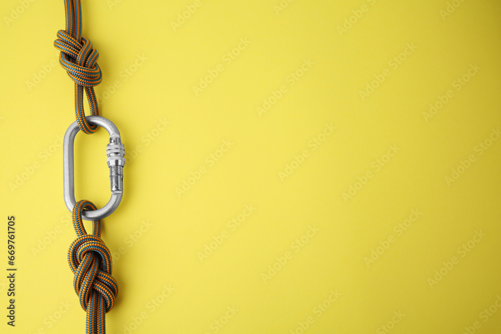 One metal carabiner with ropes on yellow background, top view. Space for text - obrazy, fototapety, plakaty 