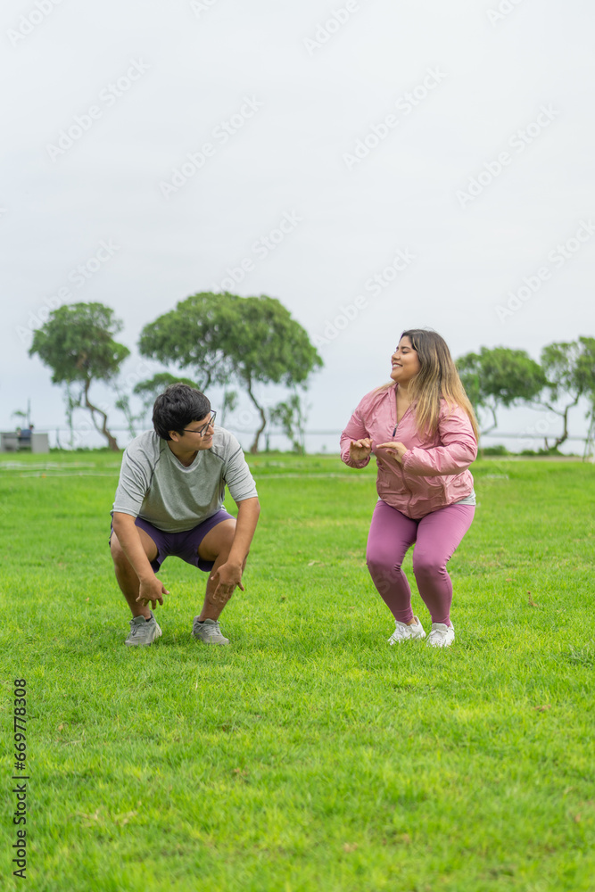 Two fat people in sports clothes jumping on a park