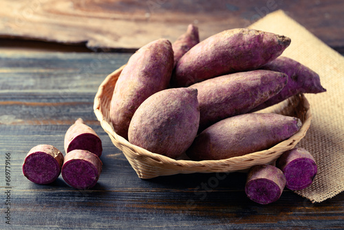 Purple sweet potato in basket on wooden background photo