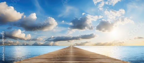 Sunny day with white clouds and sun shining over a wooden pier