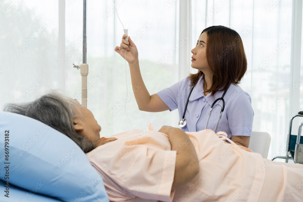 Fototapeta premium A nurse or caregiver for an elderly patient is adjusting the normal rate of medical saline given to the patient.