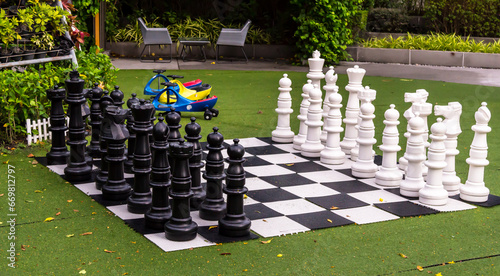 Big black and white plastic chess on chess board in playground.