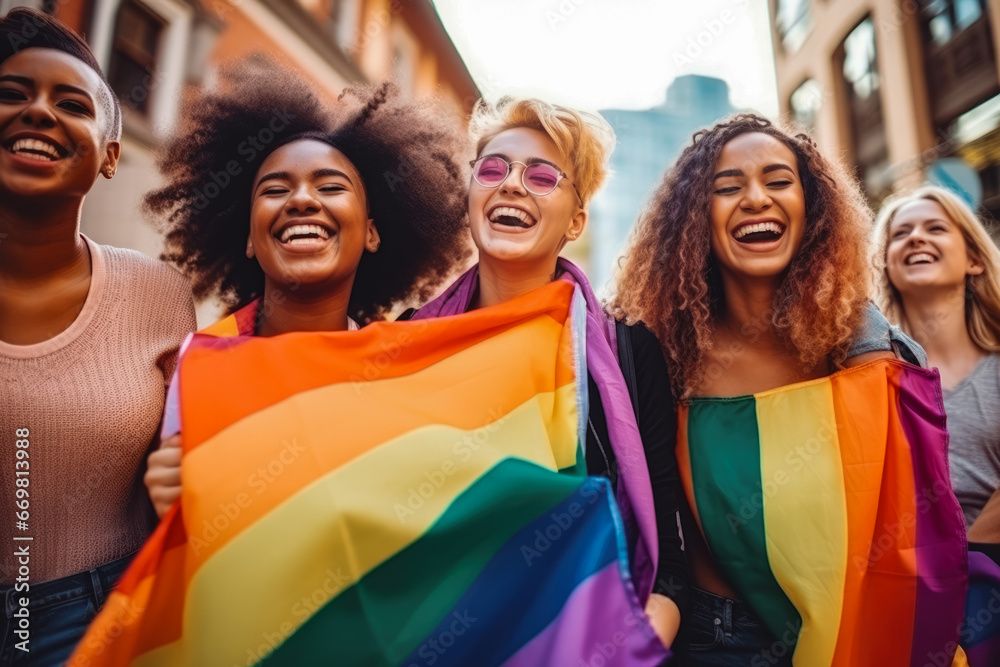 Happy group of gay people having fun and celebrating pride month together at the pride parade with colorful flag of rainbow colors - obrazy, fototapety, plakaty 