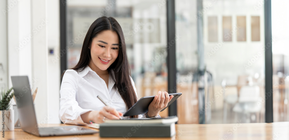 Business woman using digital tablet while working on laptop at office. Successful woman entrepreneur. Business woman using digital tablet while working on laptop at office. Successful woman entrepreneur.